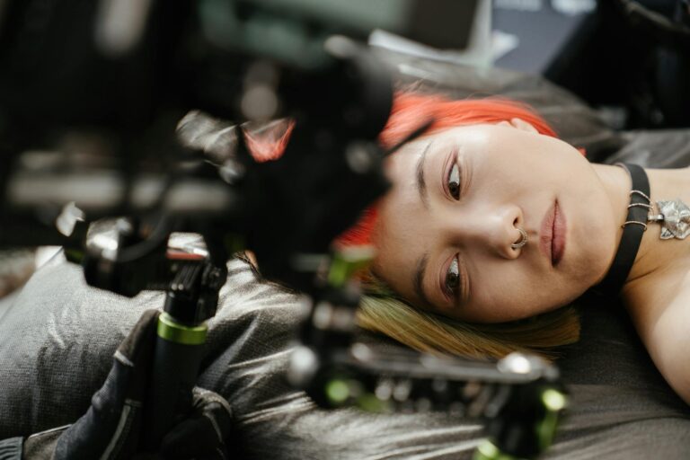 Close-up of a tattoo artist in action, captured with a focus on colorful hair and equipment.