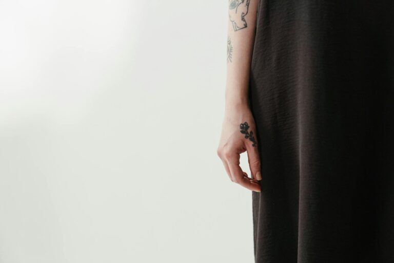 Close-up of a tattooed arm in a black dress with ample copy space, creating a minimalist, artistic look.